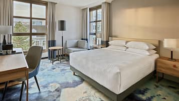 Een hotelkamer met een bed, een bureau, een stoel, een tafeltje en een lamp.