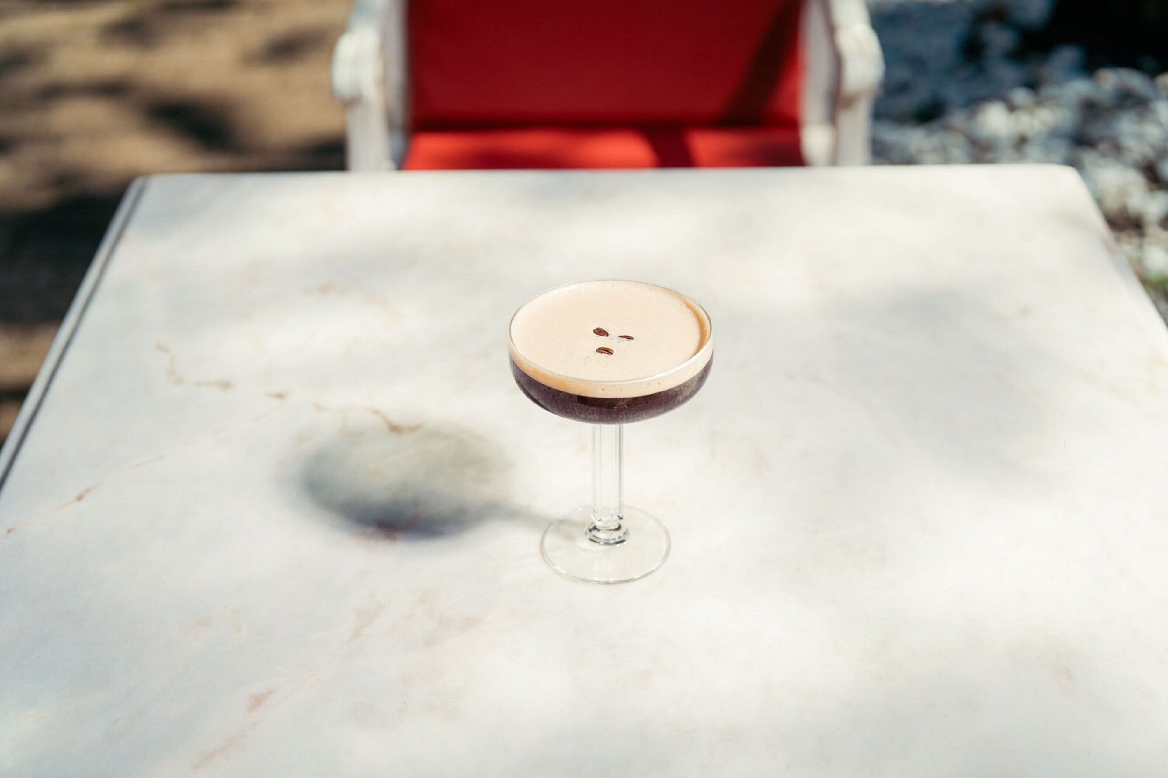 A glass of beverage on a white table with a shadow.