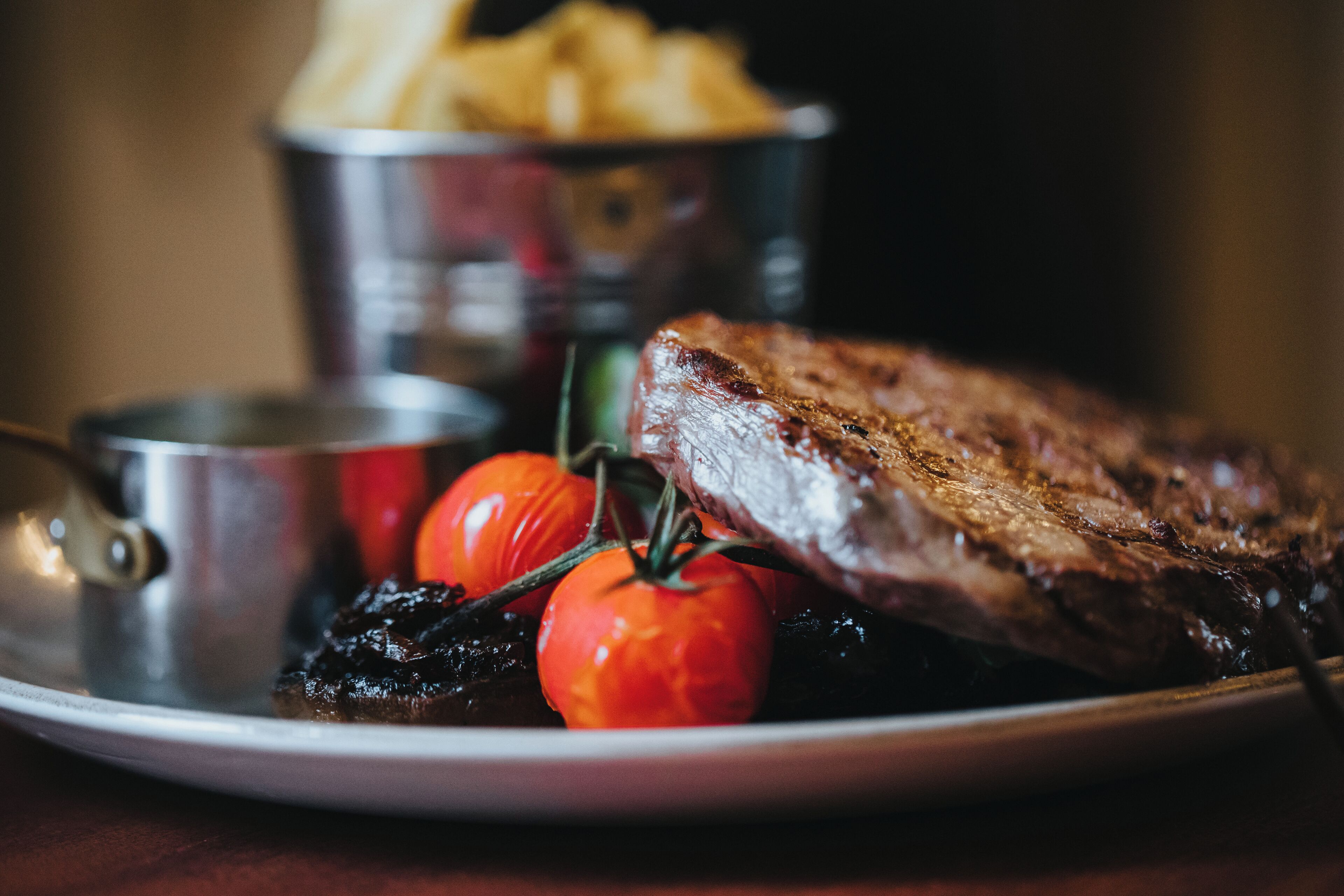 Ein Teller mit einem Steak, Kirschtomaten und Pommes Frites.
