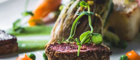 A plate with a slice of meat, asparagus, and peas.