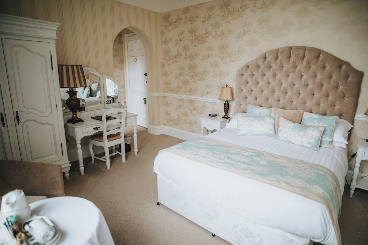A bedroom with a large bed, a dresser, a mirror, and a nightstand.