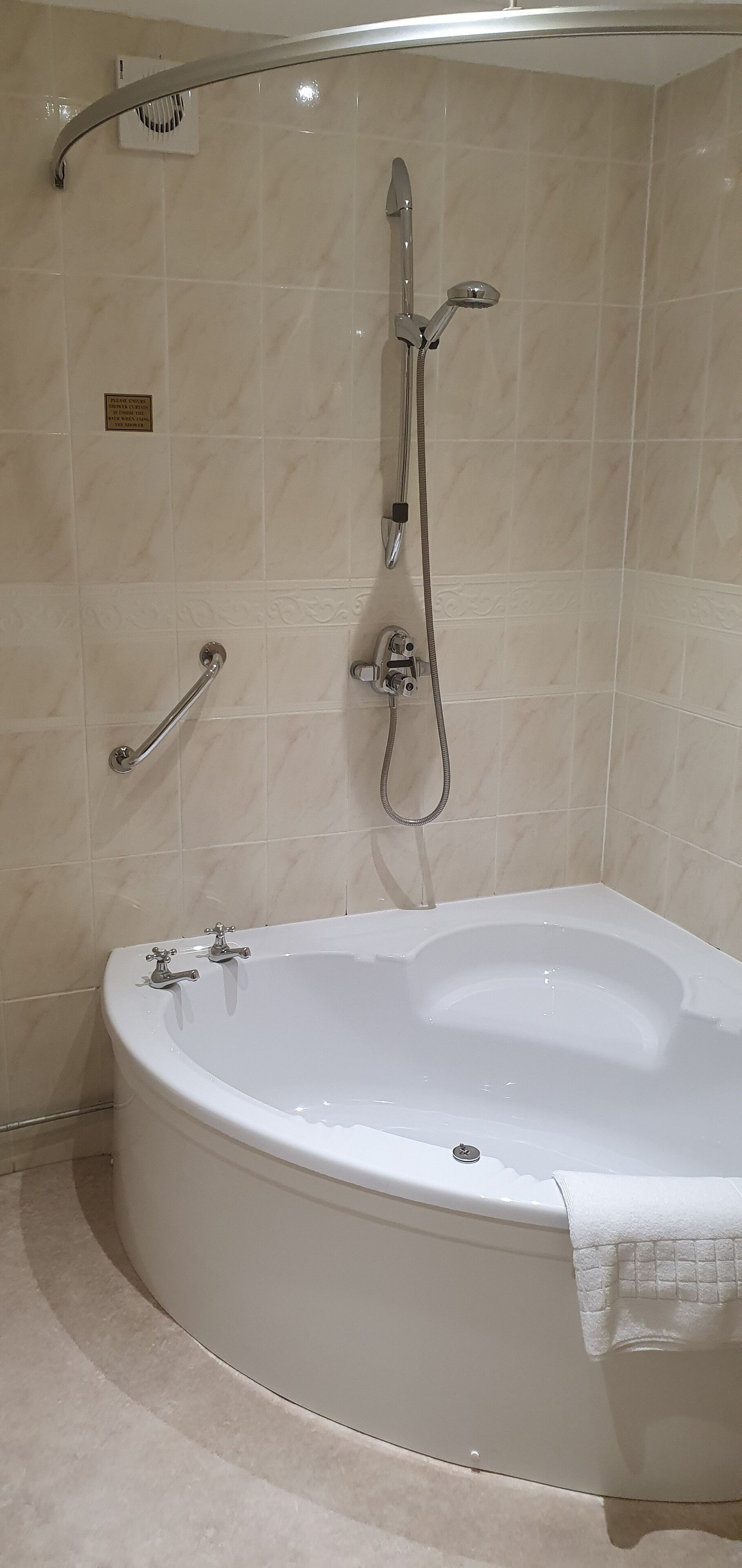 Uma casa de banho moderna com uma banheira independente, um chuveiro de mão e uma sanita de parede.