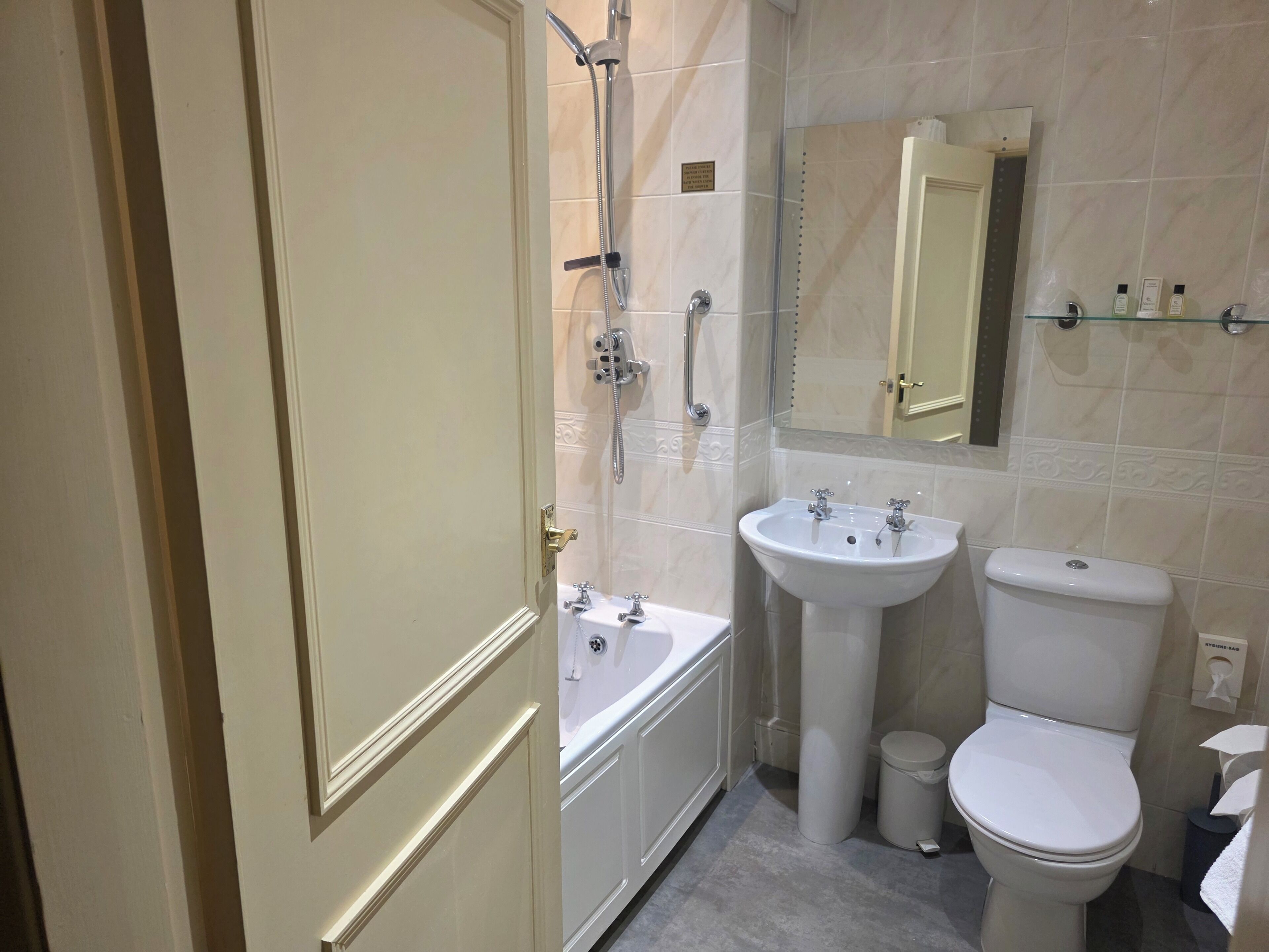 A bathroom with a bathtub, sink, toilet, and a mirror.