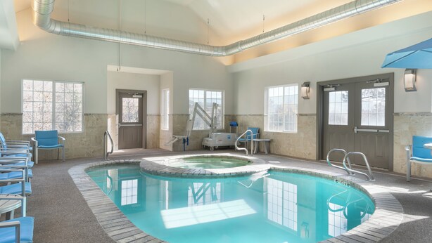 A swimming pool with a hot tub, surrounded by lounge chairs and a covered seating area.