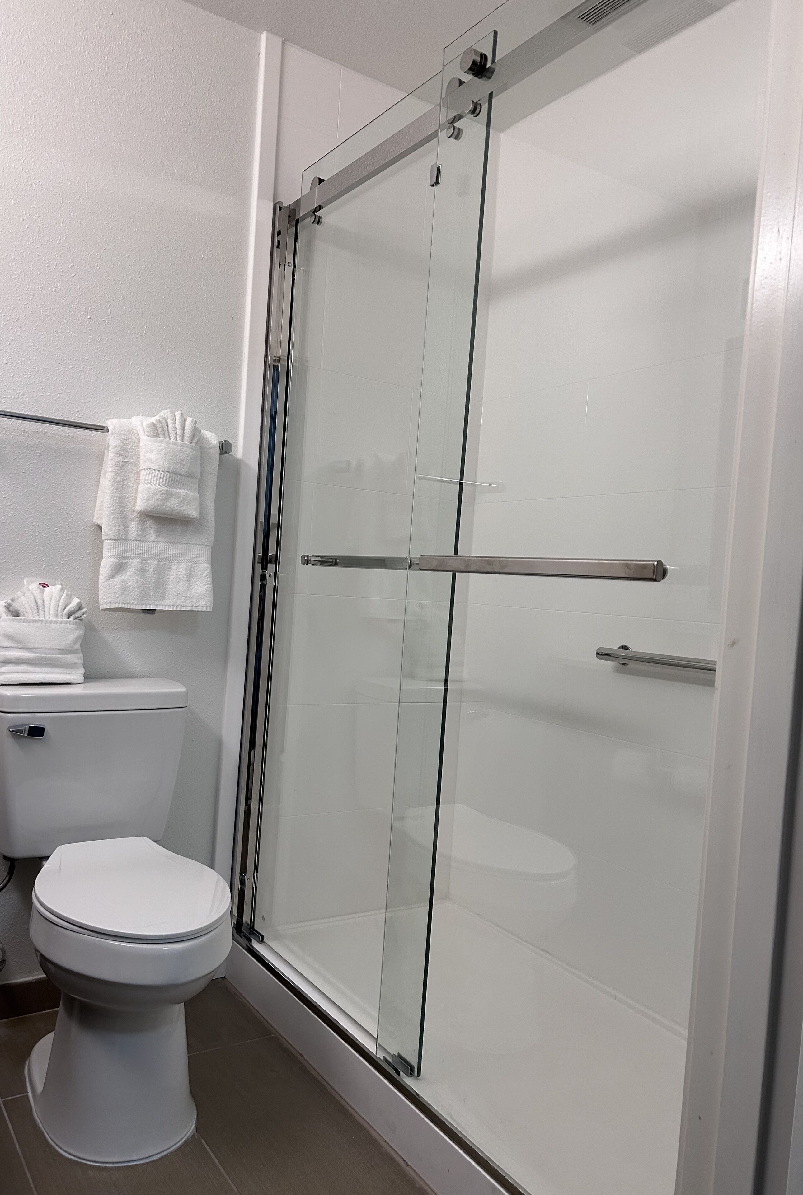 Ein modernes Badezimmer mit einer Duschkabine, einer Toilette und ordentlich gefalteten Handtüchern.