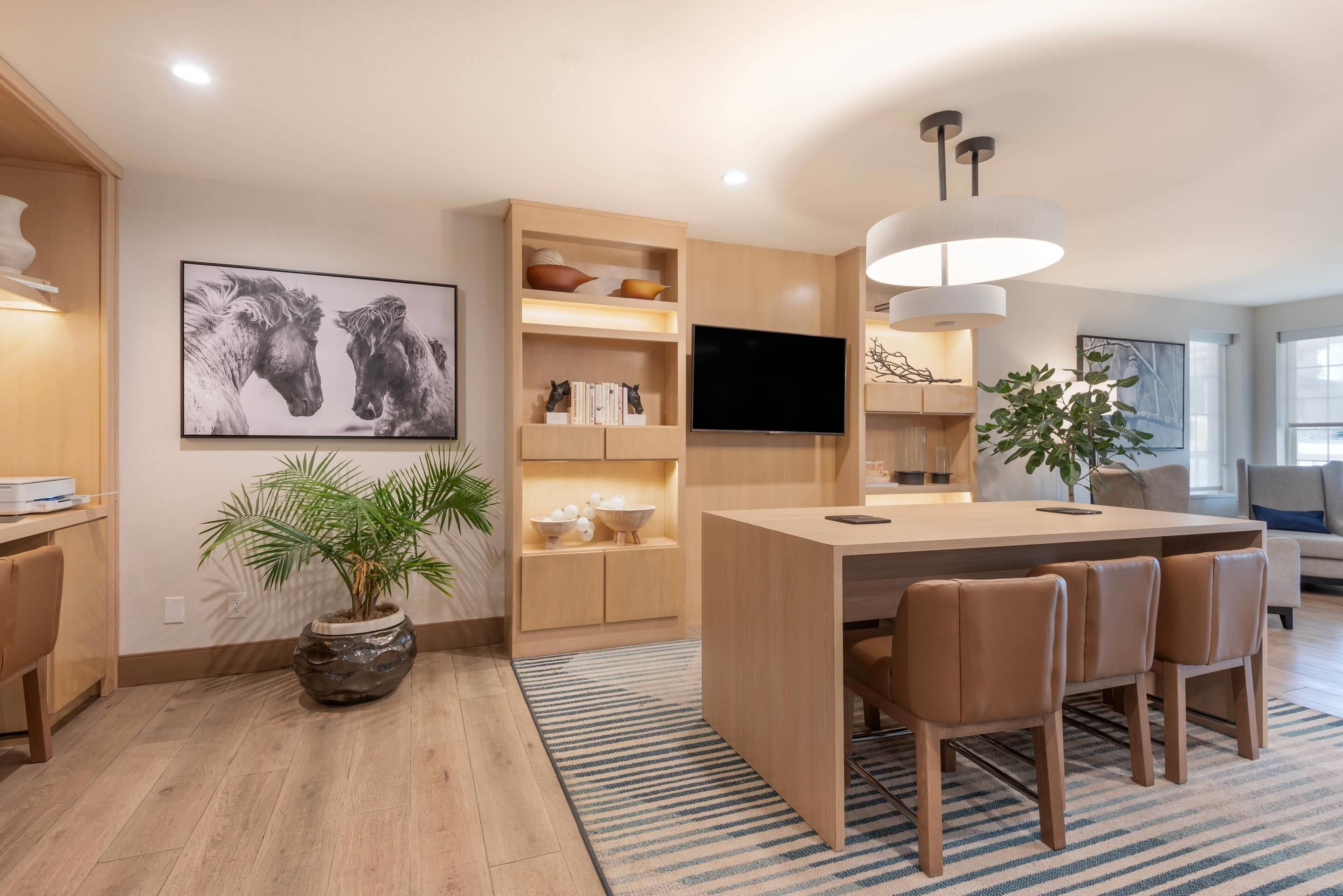 Una cocina moderna con una isla central, armarios de madera, un televisor de pantalla plana y una planta grande en maceta.