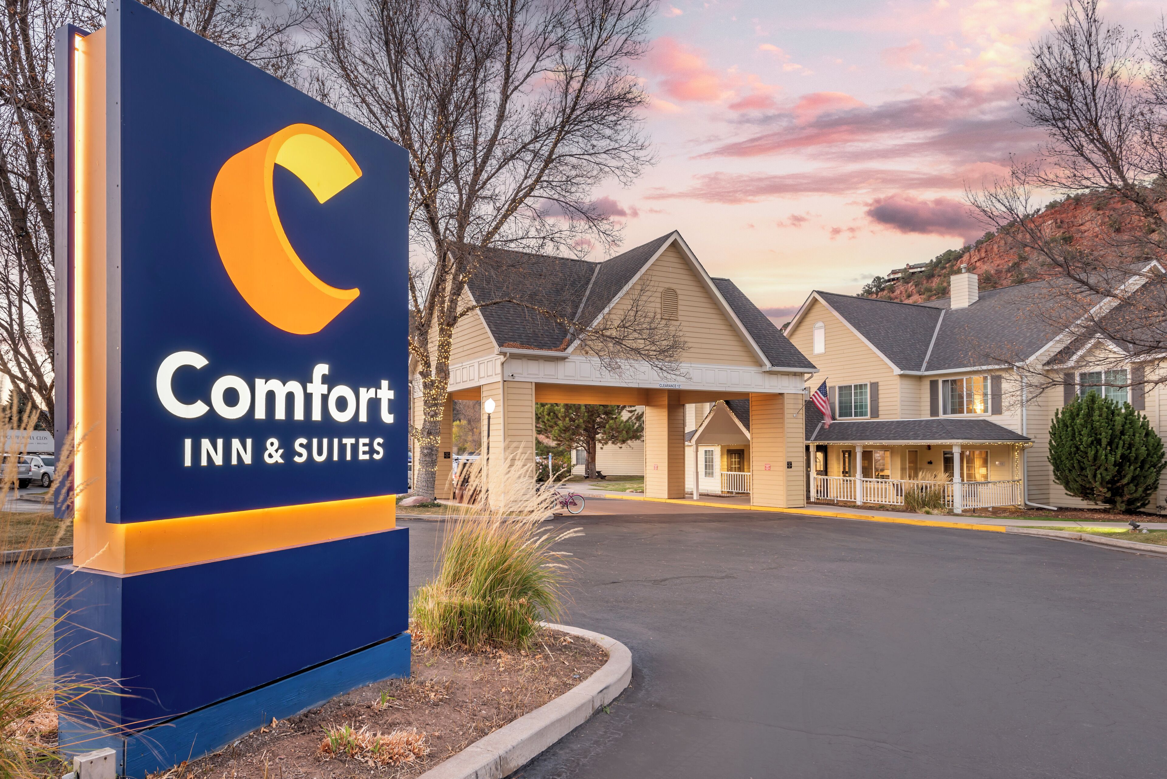 Señal de Comfort Inn & Suites con un diseño moderno, un estacionamiento techado y un edificio de estilo arquitectónico tradicional.