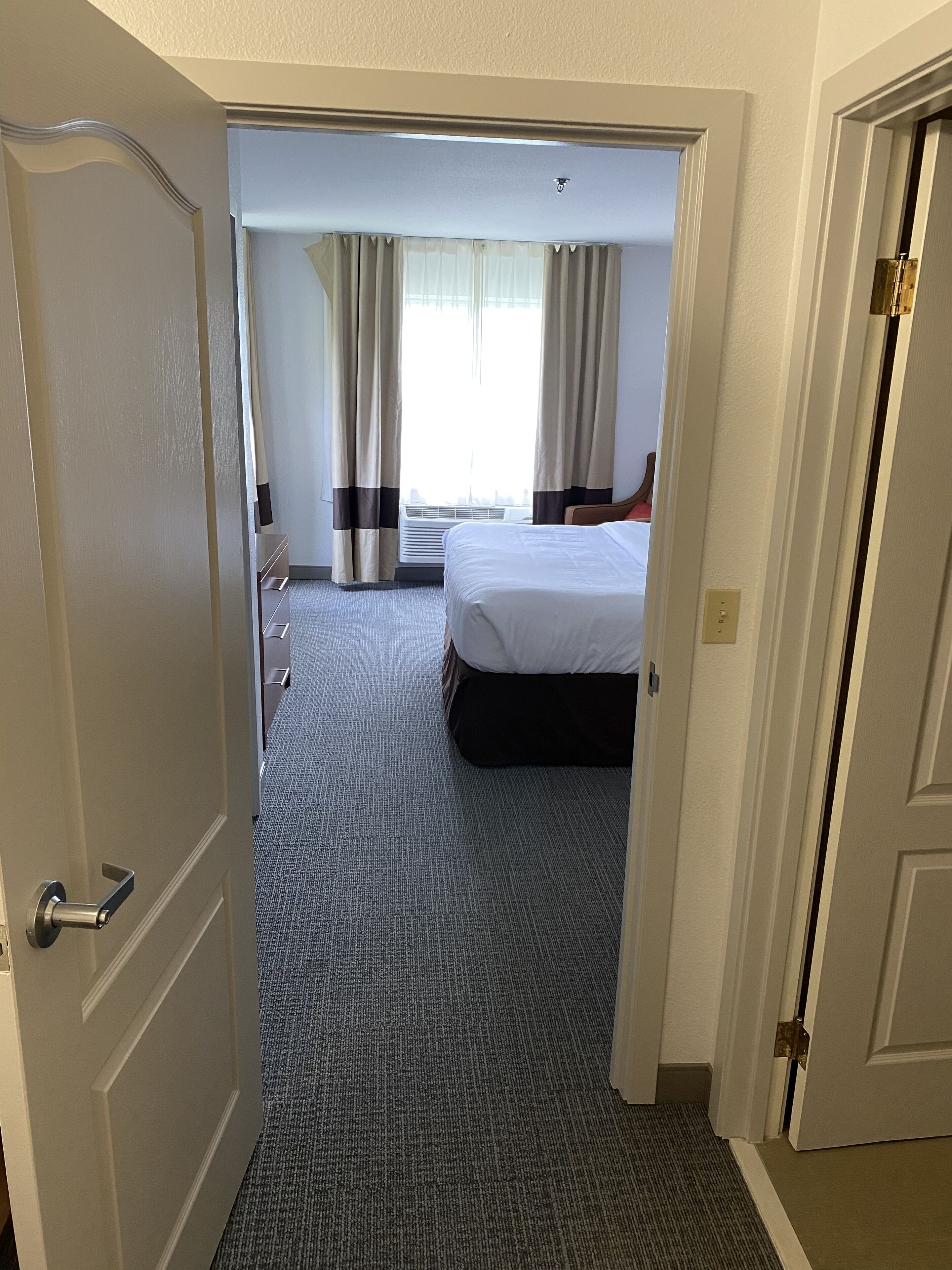 Een hotelkamer met een bed, een bureau en een raam met gordijnen.