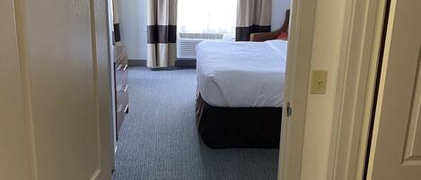 Una habitación de hotel con cama, escritorio y ventana con cortinas.