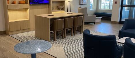 A modern hotel lobby with a bar area, seating, and a television.