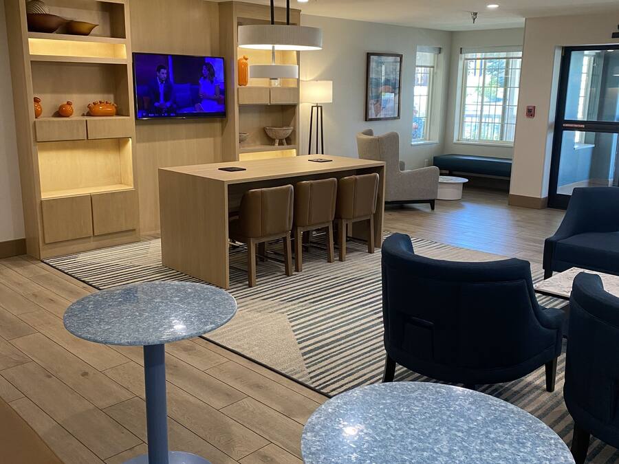 A modern hotel lobby with a bar area, seating, and a television.
