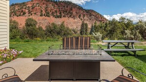 An outdoor patio with a fire pit, seating, and a picnic table.