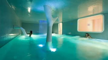 Une piscine intérieure dotée d’une conception architecturale unique, comprenant une grande colonne centrale et un mur en verre.