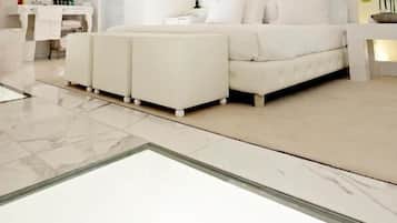 A modern bedroom with a large bed, a sitting area with chairs, and a dining table with chairs.