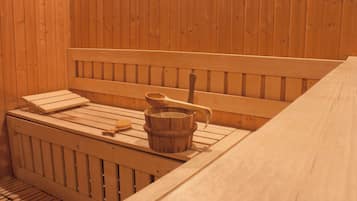 Un sauna en bois avec des bancs, un seau en bois et une brosse en bois.
