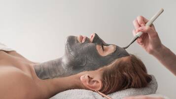 Una persona recibiendo un tratamiento facial con una mascarilla negra.