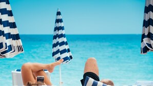 Eine Strandlounge mit gestreiften Sonnenschirmen und Liegestühlen mit Blick aufs Meer.