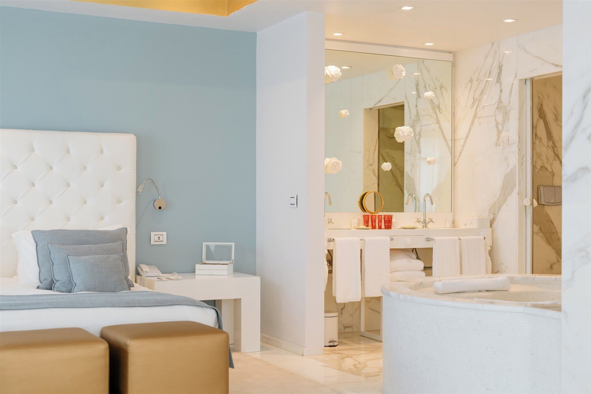 A modern bedroom with a tufted headboard, bedside table, and a large mirror.
