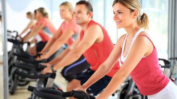 A group of people on stationary bikes in a well-lit indoor space with large windows.