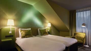 Habitación de hotel con dos camas, paredes verdes y diseño moderno.