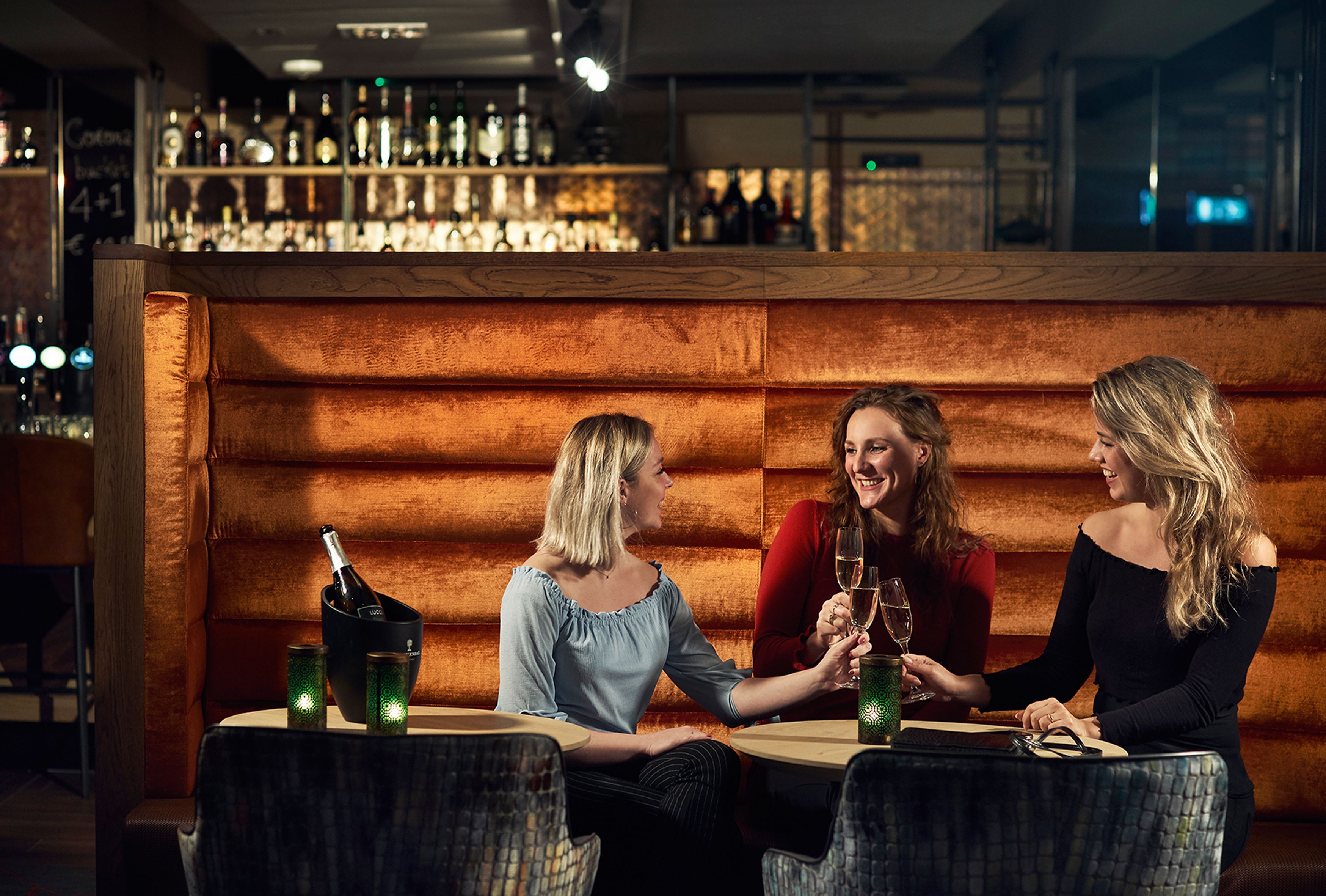 A bar area with wooden paneling, a bar counter, and a selection of bottles.