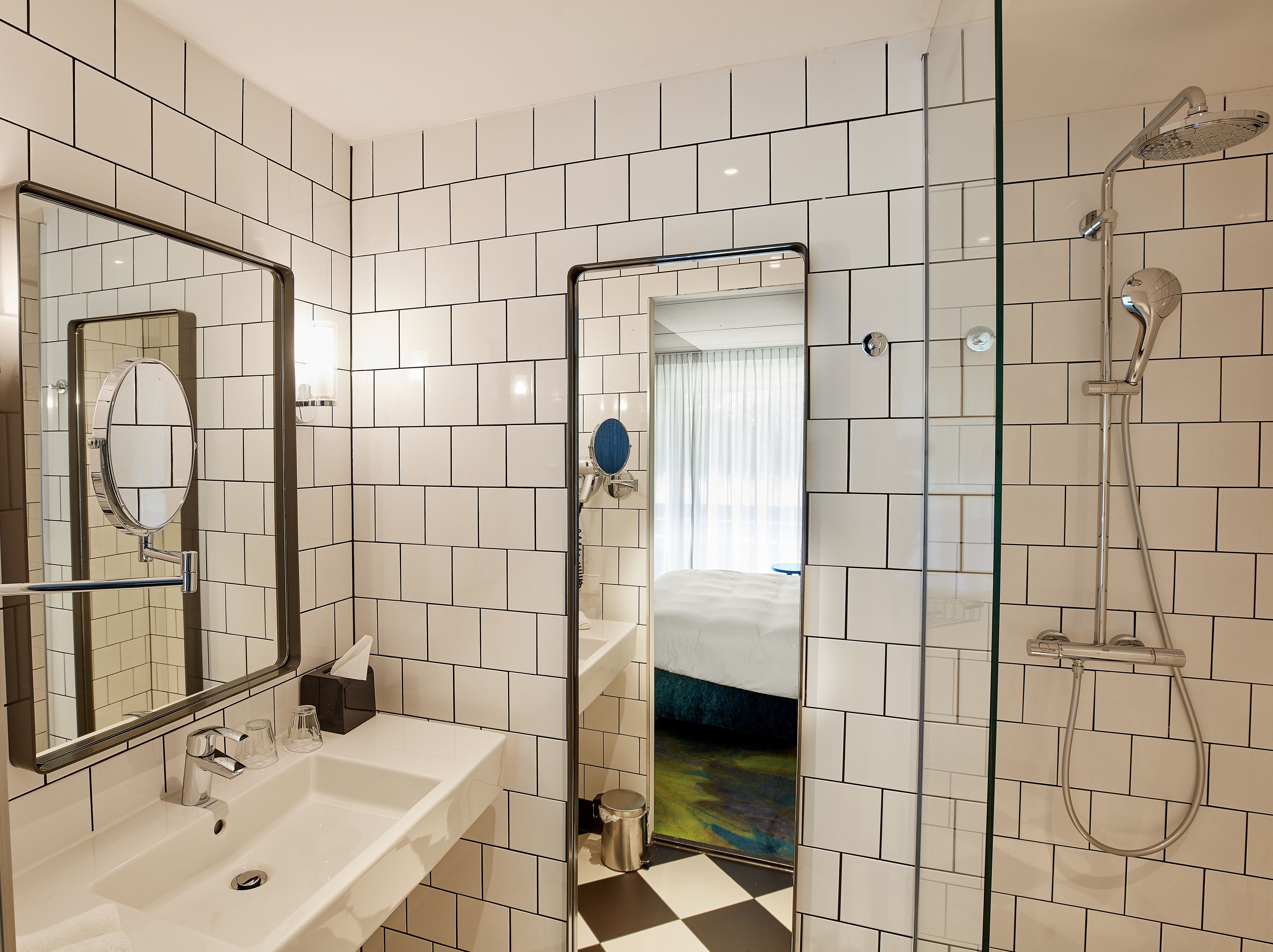 Un baño moderno con un espejo grande, un lavamanos y una ducha.