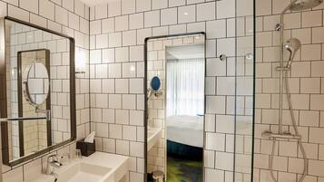 Un baño moderno con un espejo grande, un lavamanos y una ducha.
