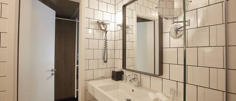 A bathroom with a white sink, mirror, and towel rack. There is a door leading to another room.