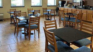 A dining area with multiple tables and chairs, a clock on the wall, and large windows allowing natural light. - Days Inn by Wyndham Gettysburg (Gettysburg)