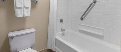 A bathroom with a toilet, a bathtub, and a shower area.