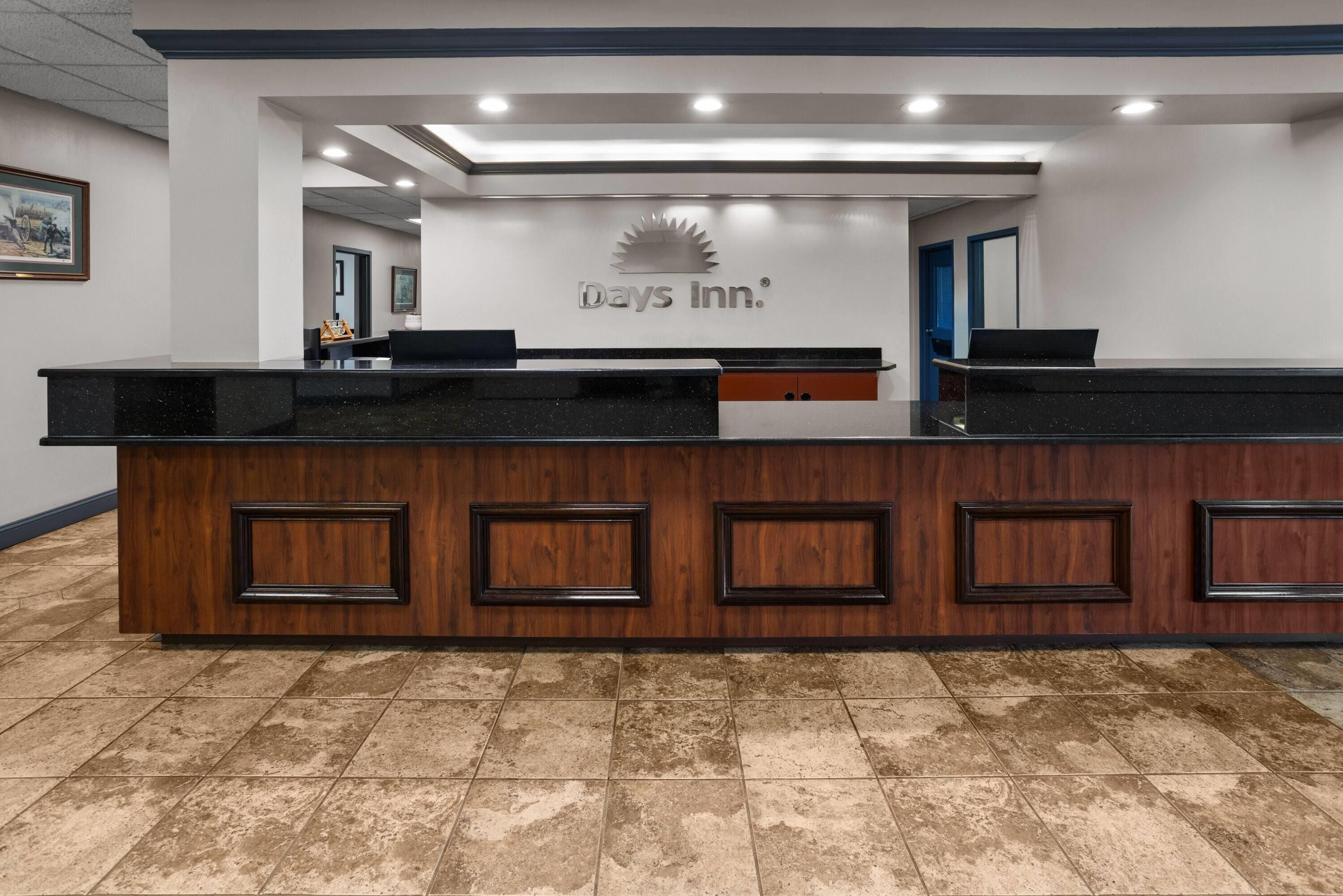 A reception desk with a Days Inn logo, a wooden panel design, and a tiled floor.