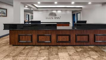A reception desk with a Days Inn logo, a wooden panel design, and a tiled floor.