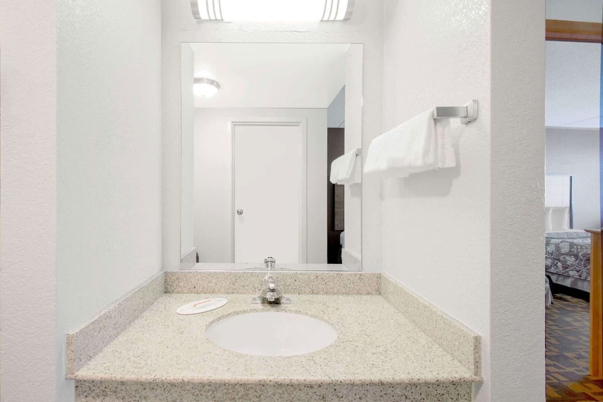 A bathroom with a granite countertop, a sink, a mirror, and a towel rack.