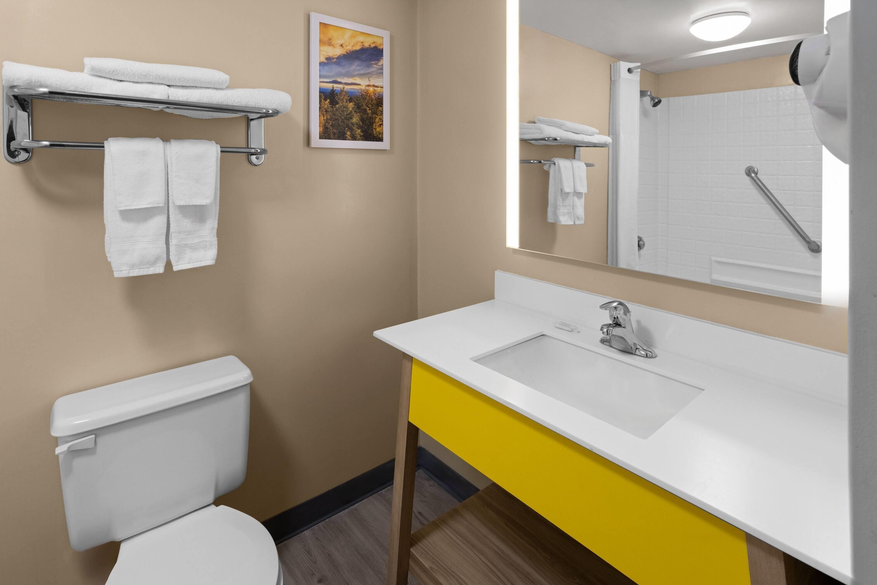 A bathroom with a toilet, a sink, a mirror, and a towel rack.