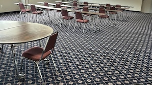 A conference room with a patterned carpet, tables, chairs, and a whiteboard. - Days Inn by Wyndham Gettysburg (Gettysburg)