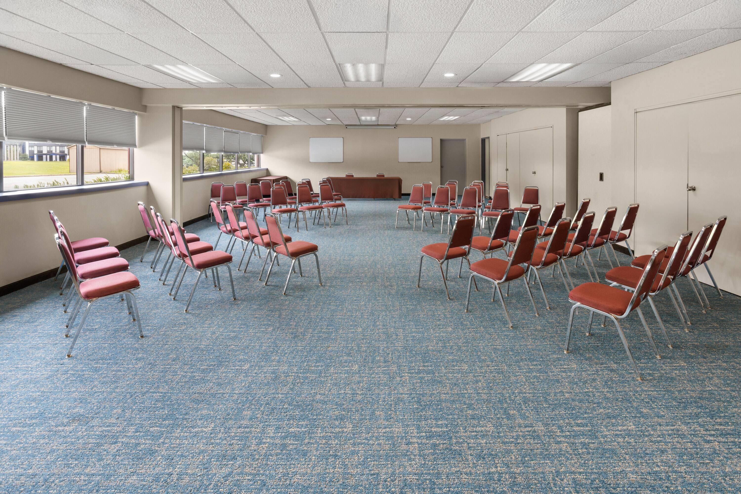 A conference room with rows of chairs, a podium, and a whiteboard.