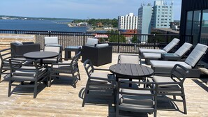 A rooftop terrace with outdoor seating, a view of the water, and city buildings in the background. - The Simon Hotel Sydney (Sydney)