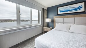 A hotel room with a large window, a bed with white linens, a nightstand with a lamp, and a framed abstract painting on the wall. - The Simon Hotel Sydney (Sydney)