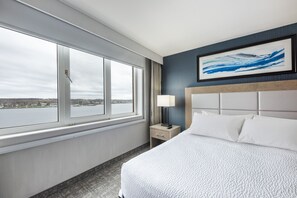 Enjoy a serene view of the water from this stylish room, featuring a comfortable bed and a unique piece of artwork.