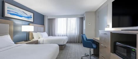 Una habitación de hotel con dos camas, un escritorio, un televisor y un microondas.