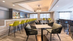 A modern bar area with a long counter, yellow bar stools, and black wicker chairs with patterned cushions. - The Simon Hotel Sydney (Sydney)