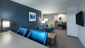 A hotel room with a dining area, a sofa set, a kitchen area, and a flat-screen TV. - The Simon Hotel Sydney (Sydney)