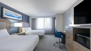 A hotel room with two beds, a desk, a television, and a microwave.