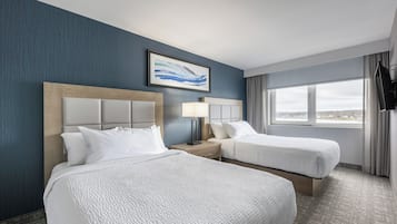Habitación de hotel con dos camas, un ventanal con vistas, un televisor de pantalla plana y un cuadro en la pared.