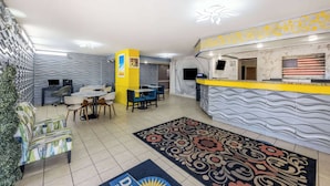 Eine Hotelhalle mit Empfangstresen, Sitzgelegenheiten und einem dekorativen Teppich.