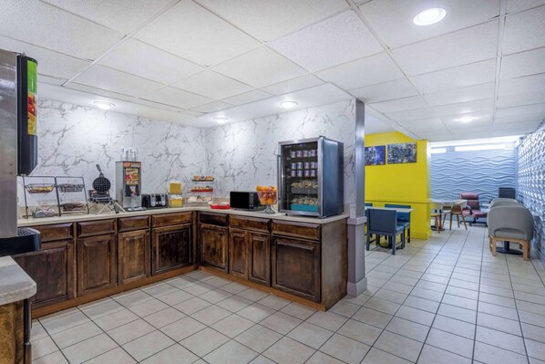 A kitchen area with a marble backsplash, wooden cabinets, a microwave, and a refrigerator.