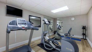 Ein Fitnessstudio mit Laufbändern, Crosstrainern und einem Ergometer.
