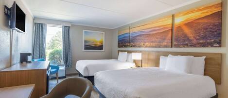 A hotel room with two beds, a desk, a chair, and a TV.