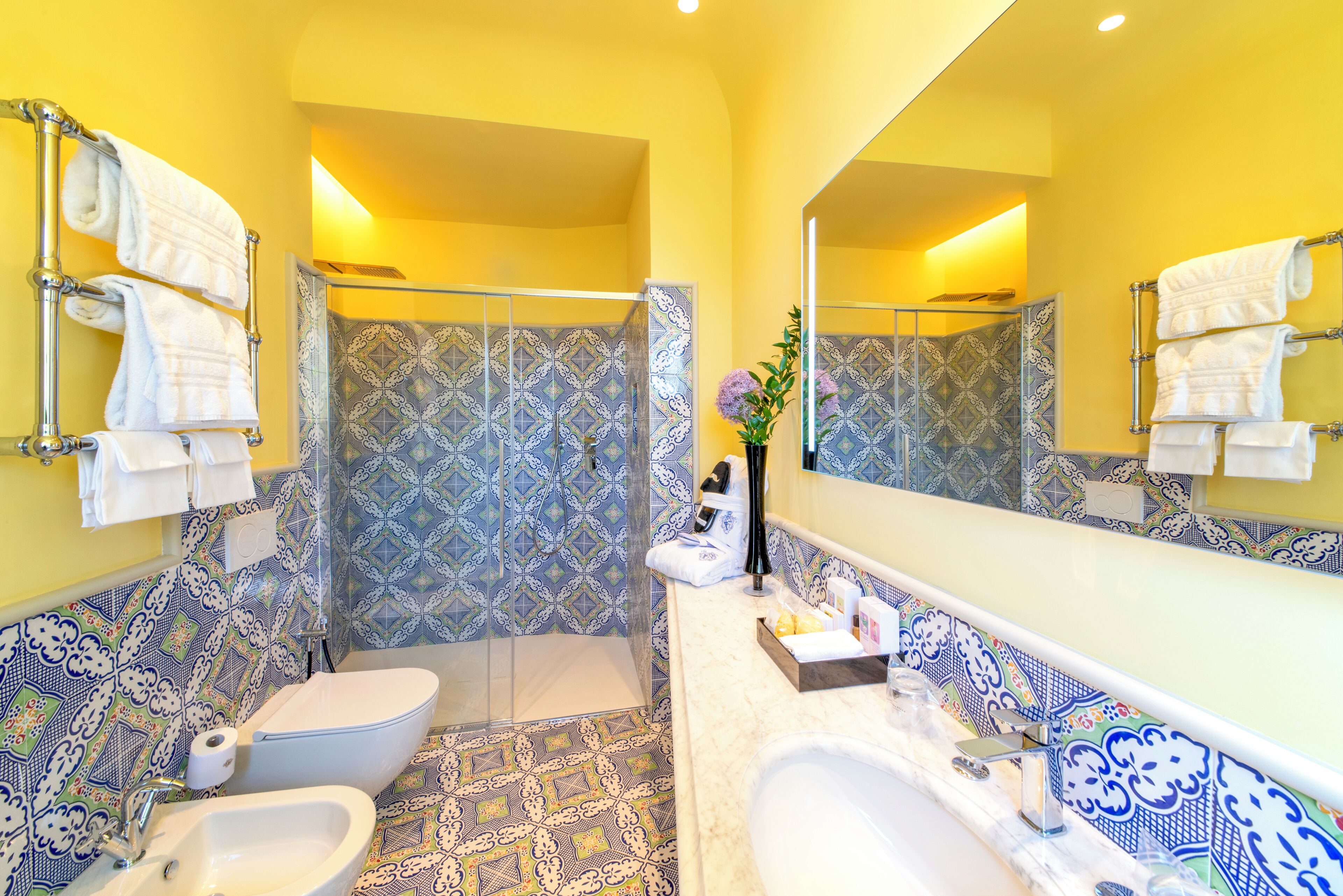 Un baño con ducha, inodoro, bidé y un espejo grande.