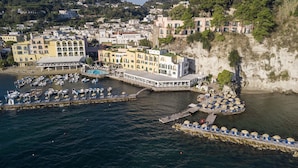 Vue aérienne d’une ville côtière avec un port de plaisance, des immeubles dotés de balcons et une falaise.